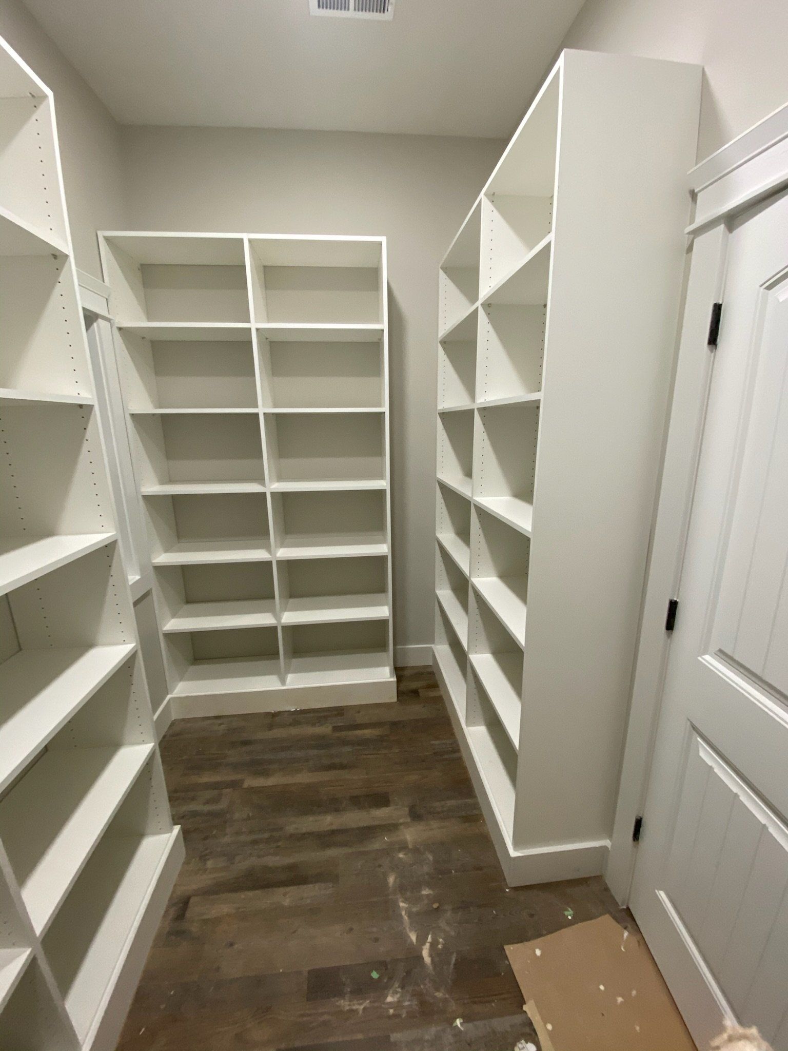 a walk in closet with lots of shelves and a wooden floor
