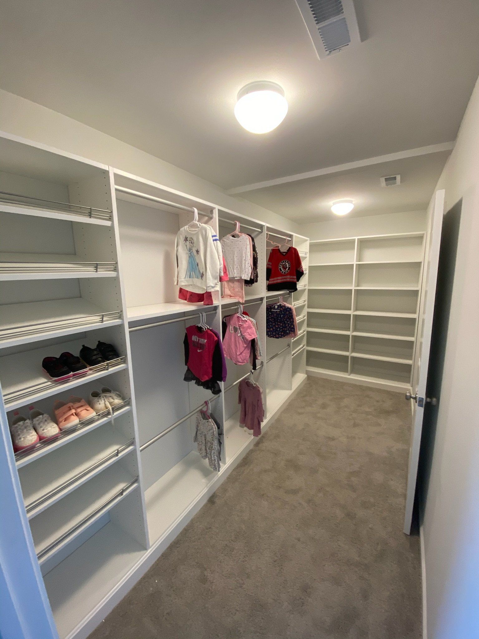 a walk in closet with lots of shelves and clothes hanging on them