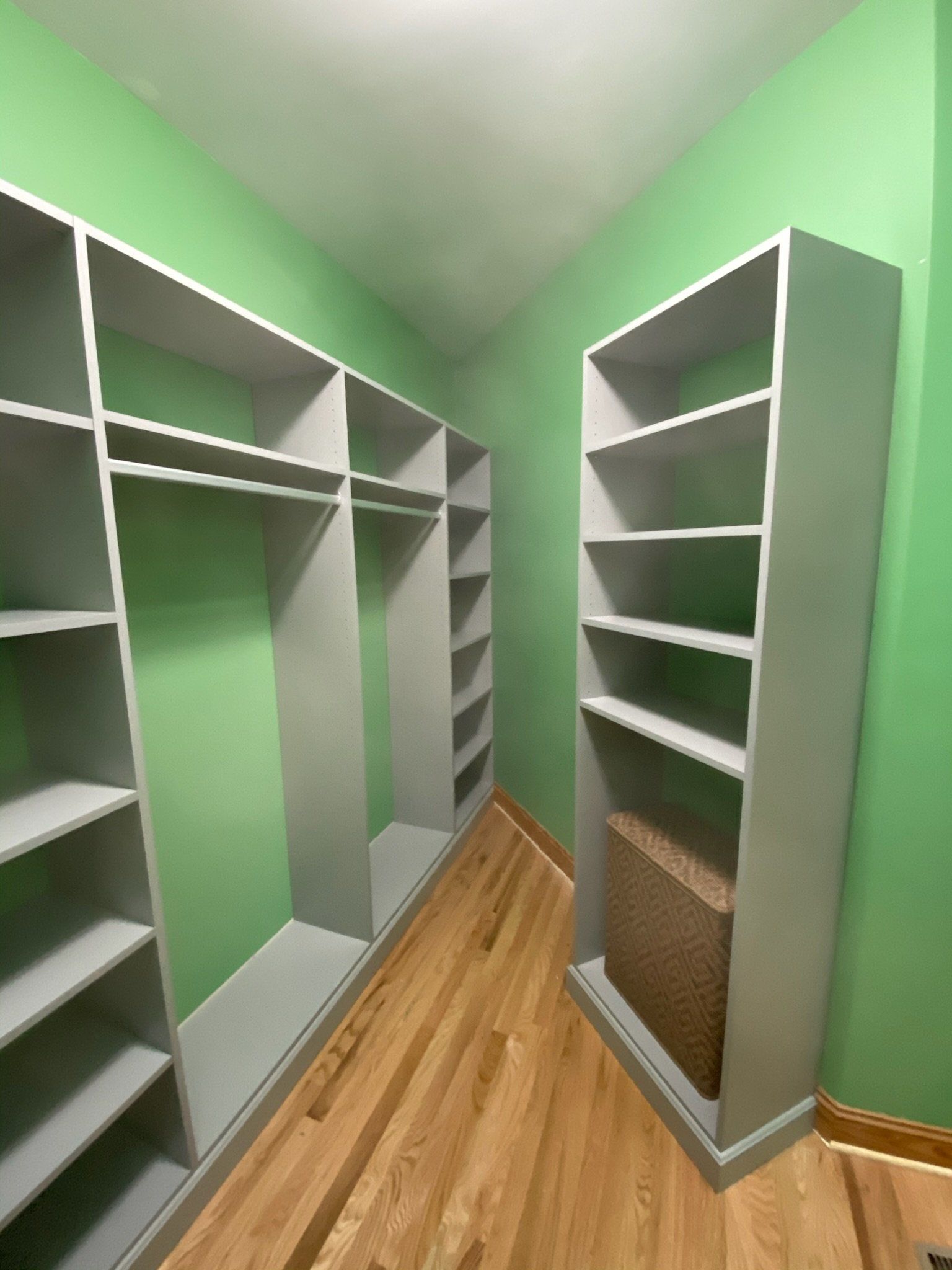 a walk in closet with green walls and white shelves