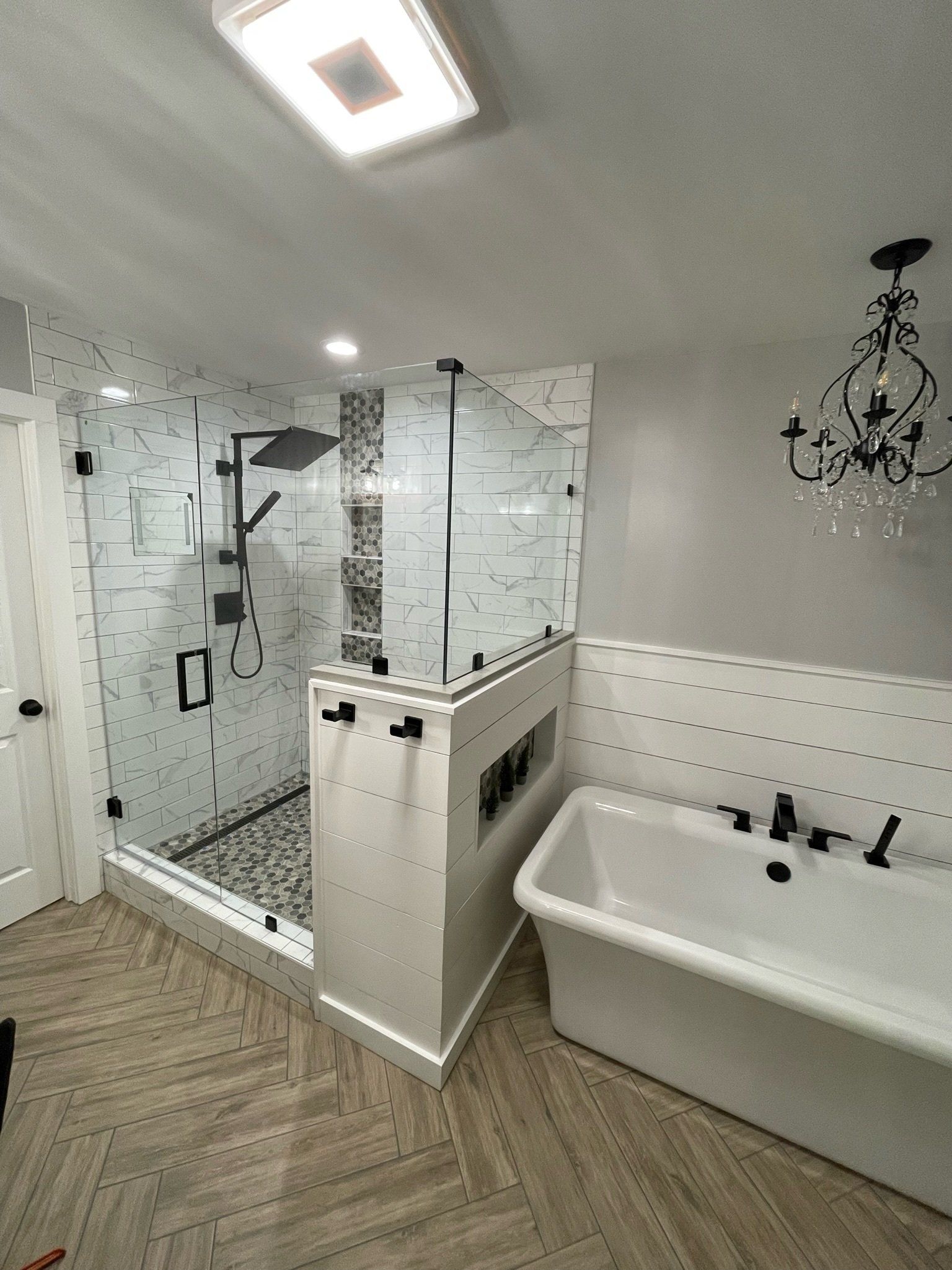 a bathroom with a tub, shower, and chandelier