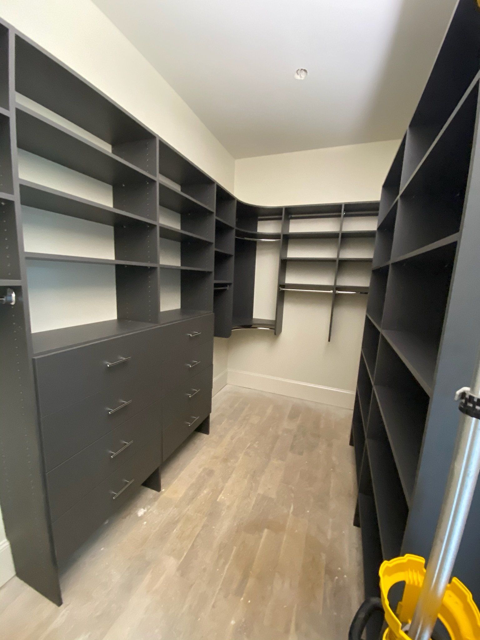 a walk in closet with lots of black shelves and drawers