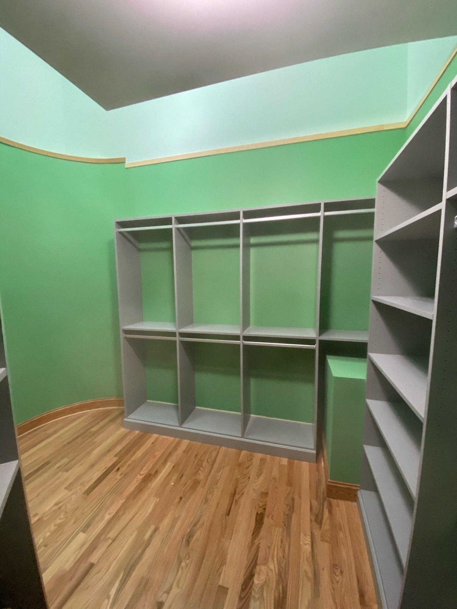 a walk in closet with green walls and wooden floors