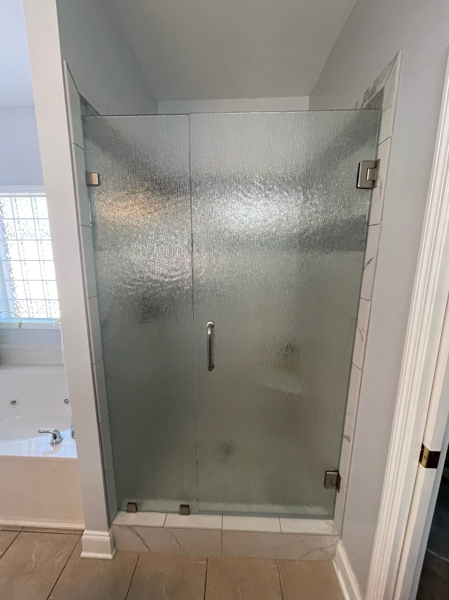 a bathroom with a frameless glass shower door and a bathtub