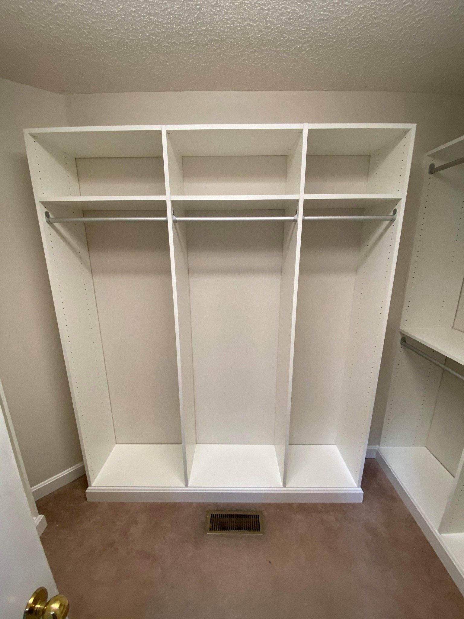 a walk in closet with white shelves and clothes racks