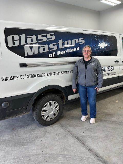 A woman is standing in front of a glass masters van.