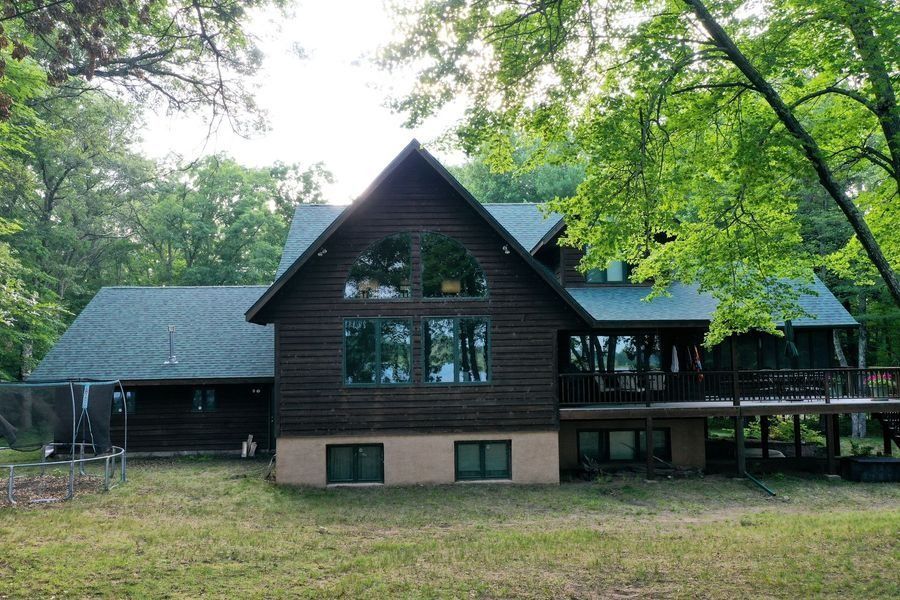 Wooden cabin in a wooded area with large windows and a covered porch