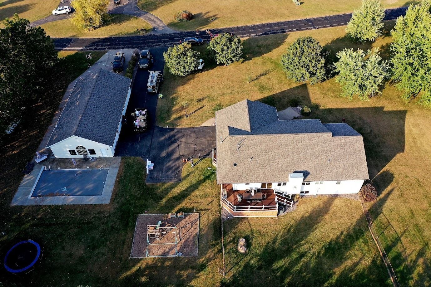 Aerial view of a rural property with two houses, a driveway, and a backyard pool.