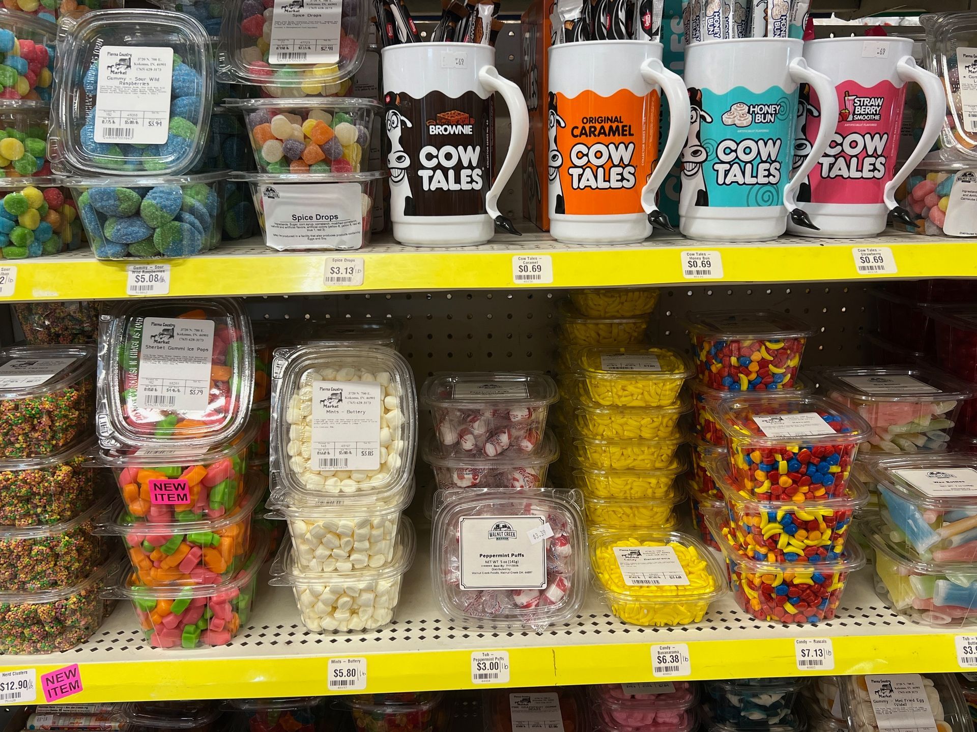 A shelf in a store filled with candy and mugs.