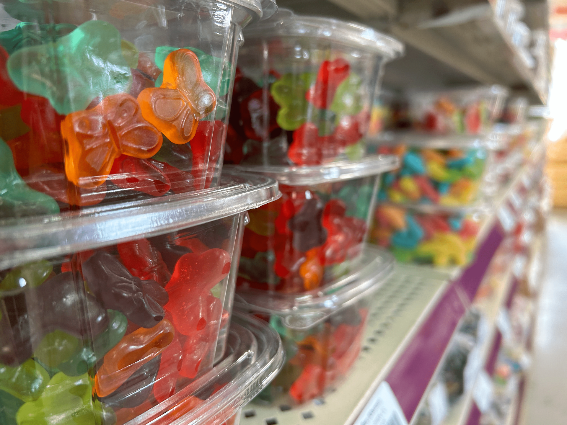 A shelf filled with plastic cups of gummy bears in a store.