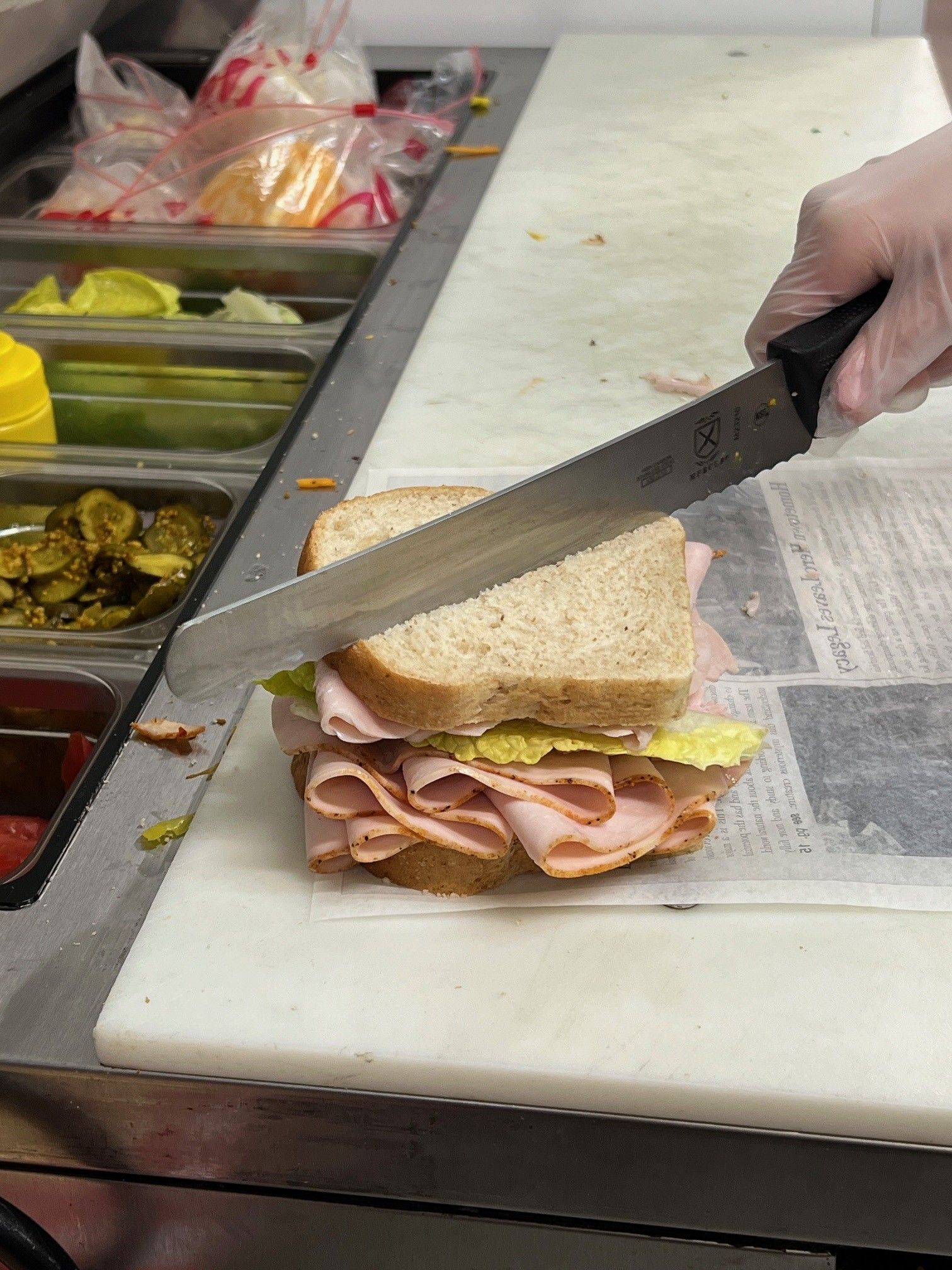 A person is cutting a sandwich on a cutting board.