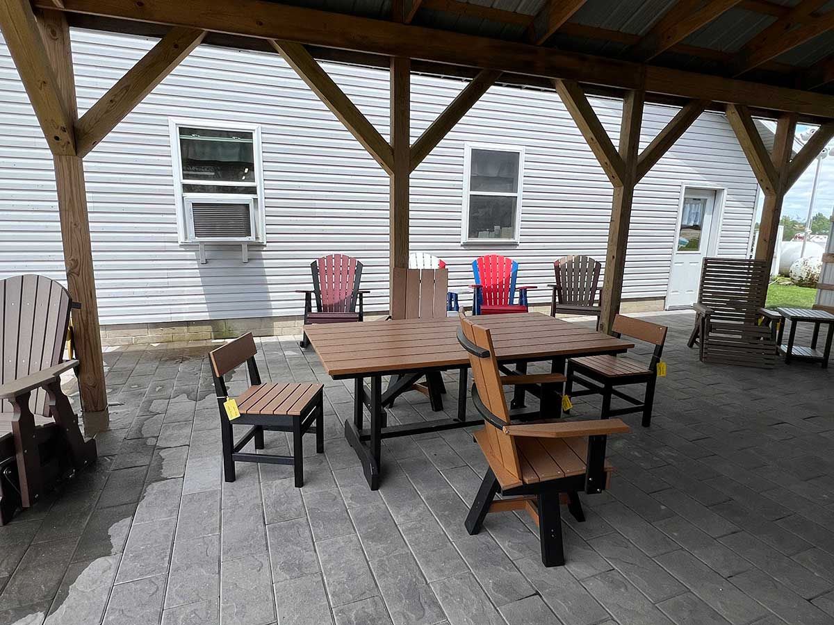 A patio with a table and chairs under a covered area.