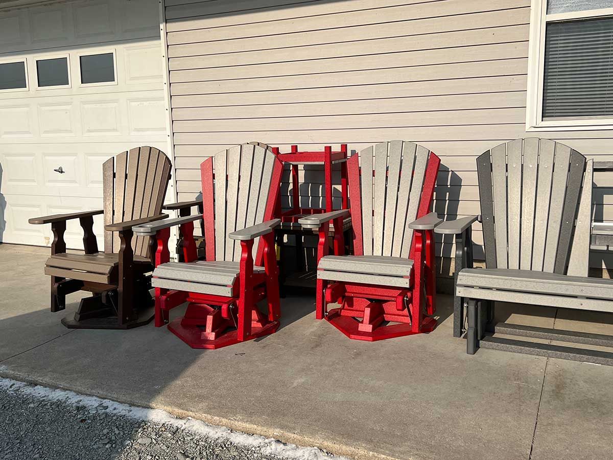 A row of rocking chairs are lined up in front of a house.