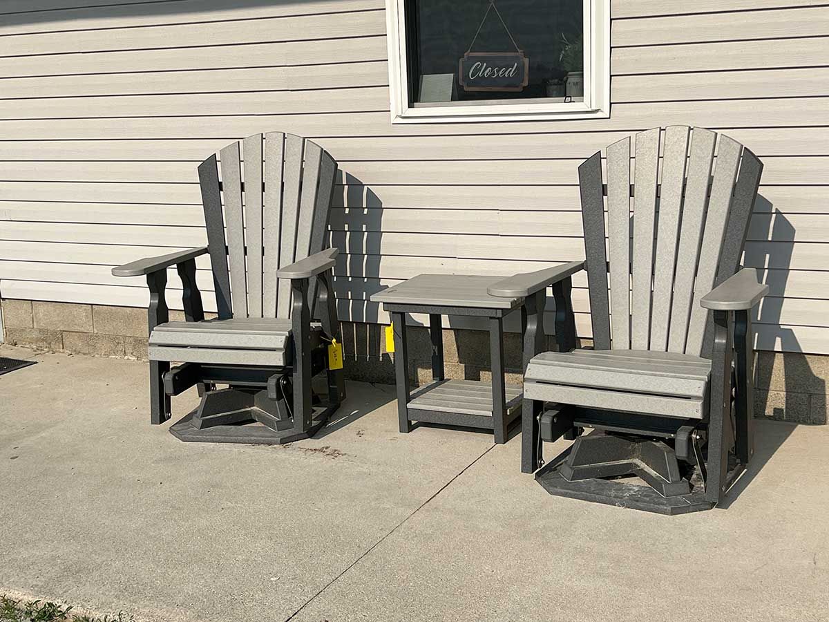 Two lawn chairs and a table are sitting on a patio in front of a house.
