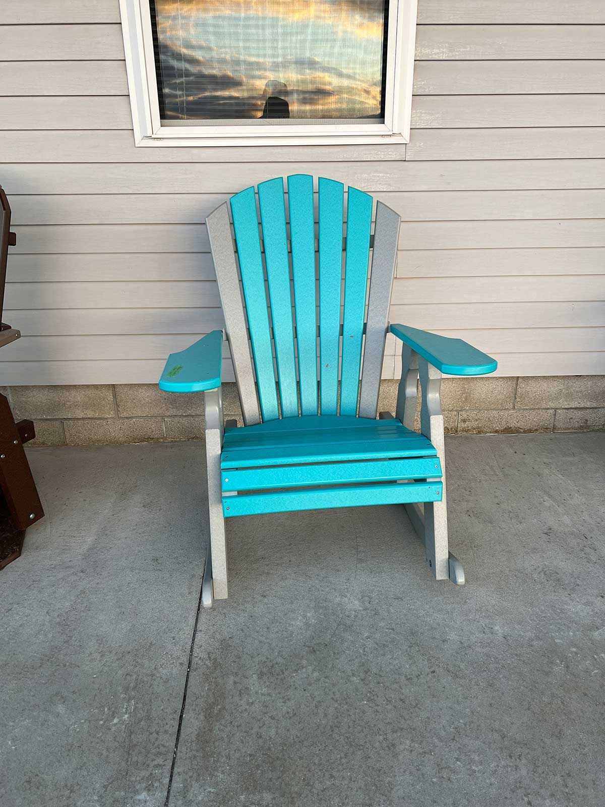 A blue and gray rocking chair is sitting in front of a house.