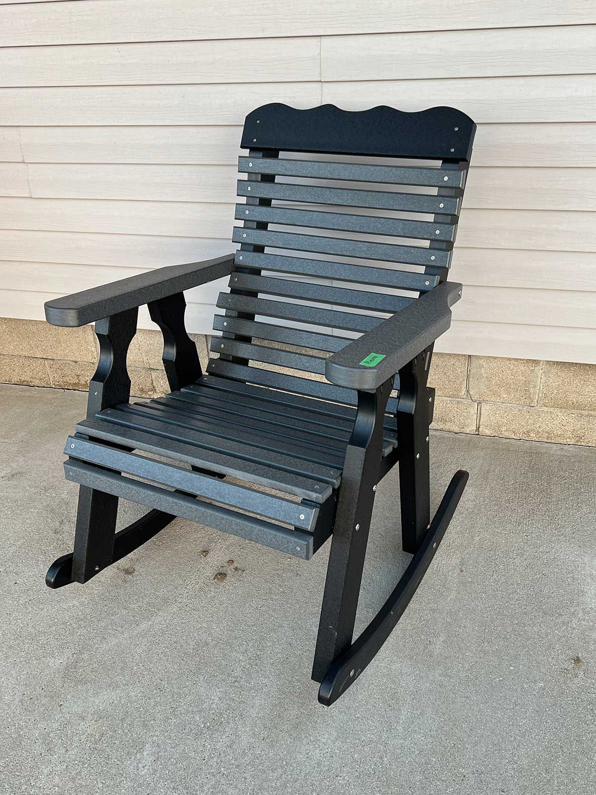 A black wooden rocking chair is sitting in front of a white wall.