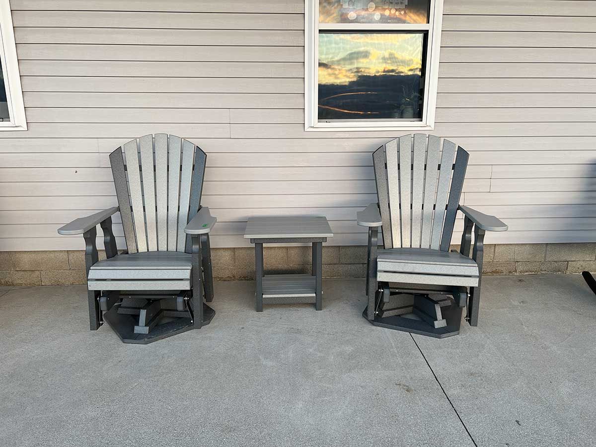 Two lawn chairs and a table are sitting in front of a house.