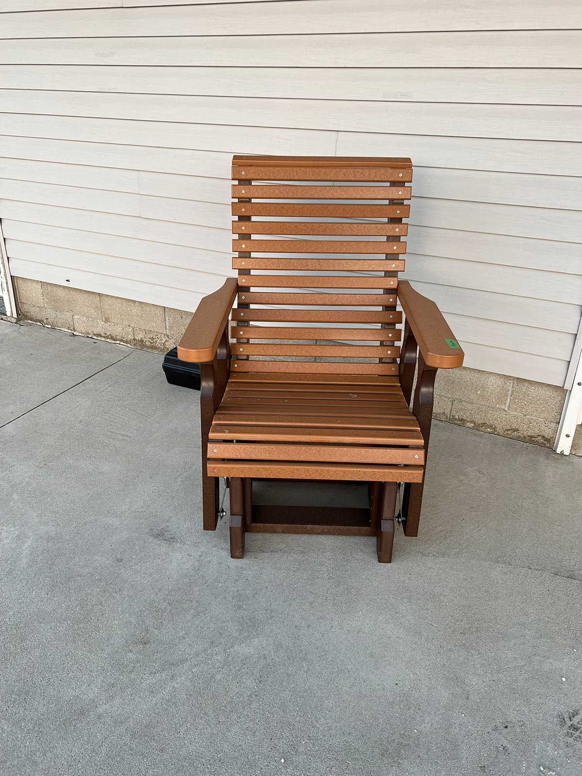 A wooden chair and ottoman are sitting on a concrete patio.