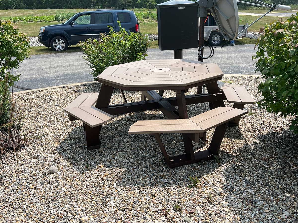 A picnic table with benches and a car parked in the background