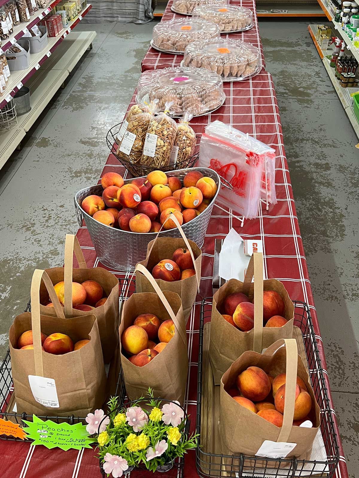 A table in a grocery store filled with bags of peaches.