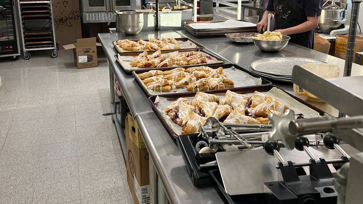 A bakery with a lot of trays of food on the counter.