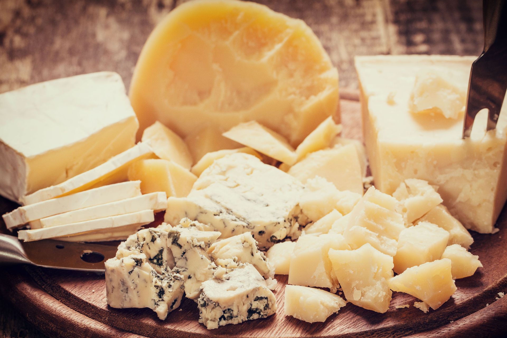 There are many different types of cheese on the cutting board.