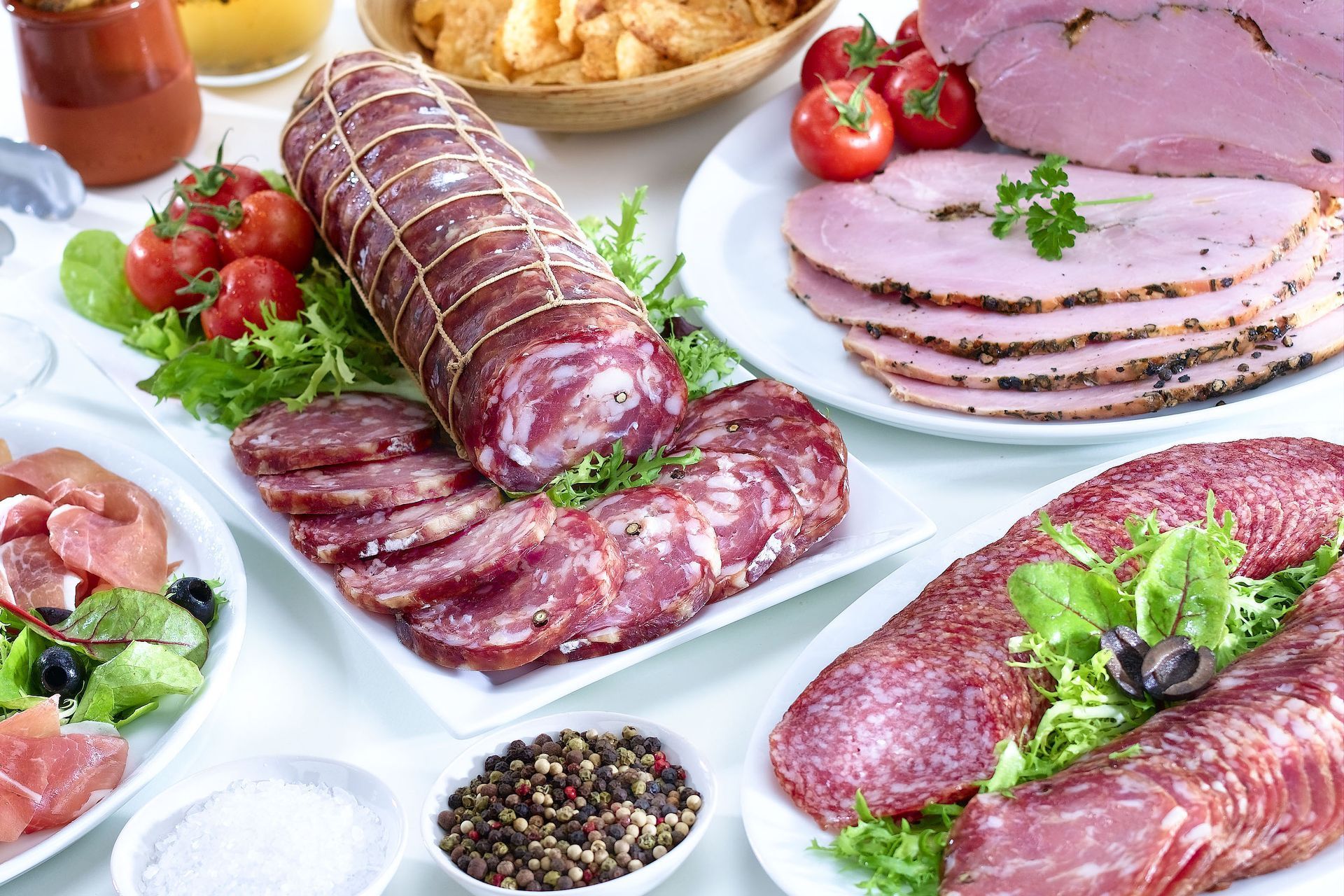 A variety of meats and vegetables are on plates on a table.