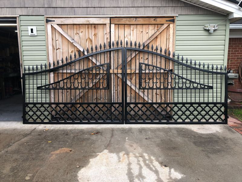 A black gate is sitting in front of a garage door.