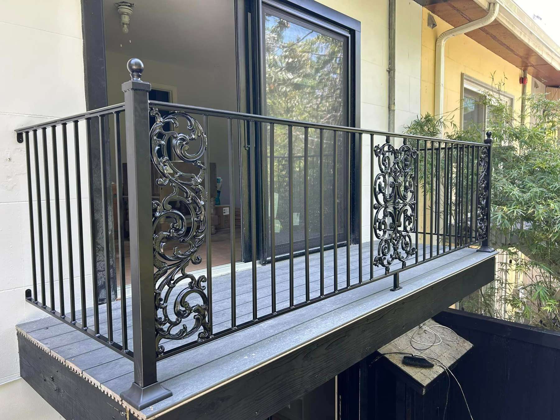 A balcony with a wrought iron railing and a sliding glass door.