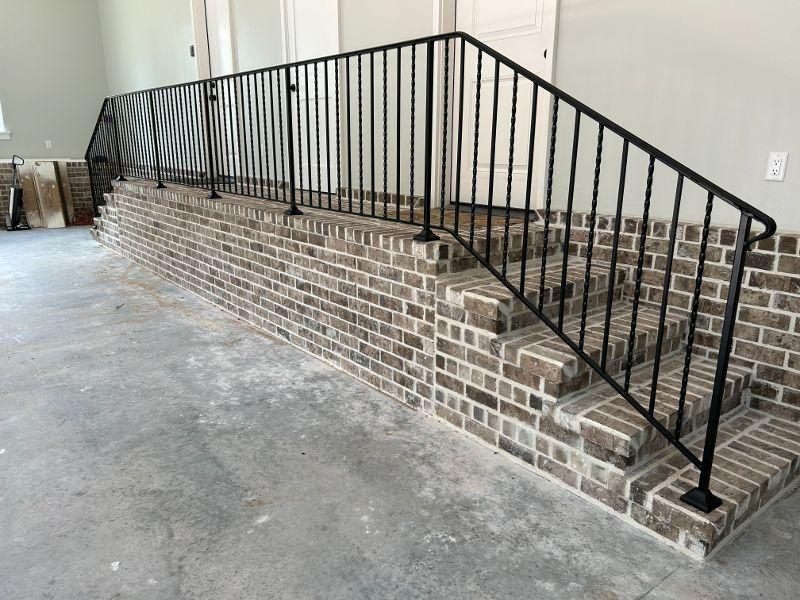 A brick wall with stairs and a wrought iron railing