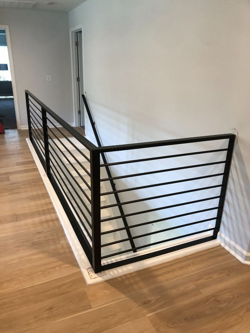 A staircase with a black railing and a wooden floor.