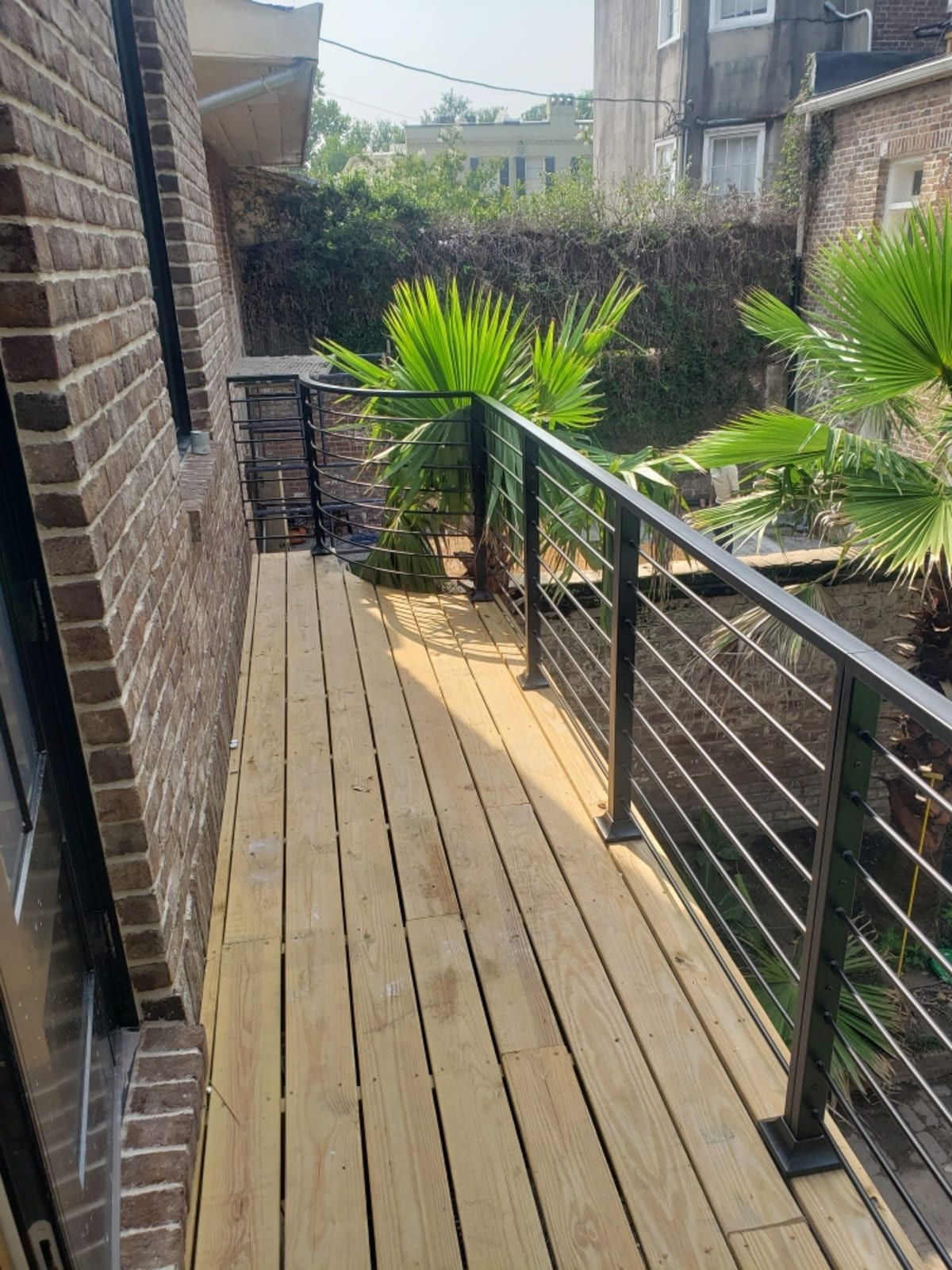 A wooden deck with a metal railing next to a brick building.