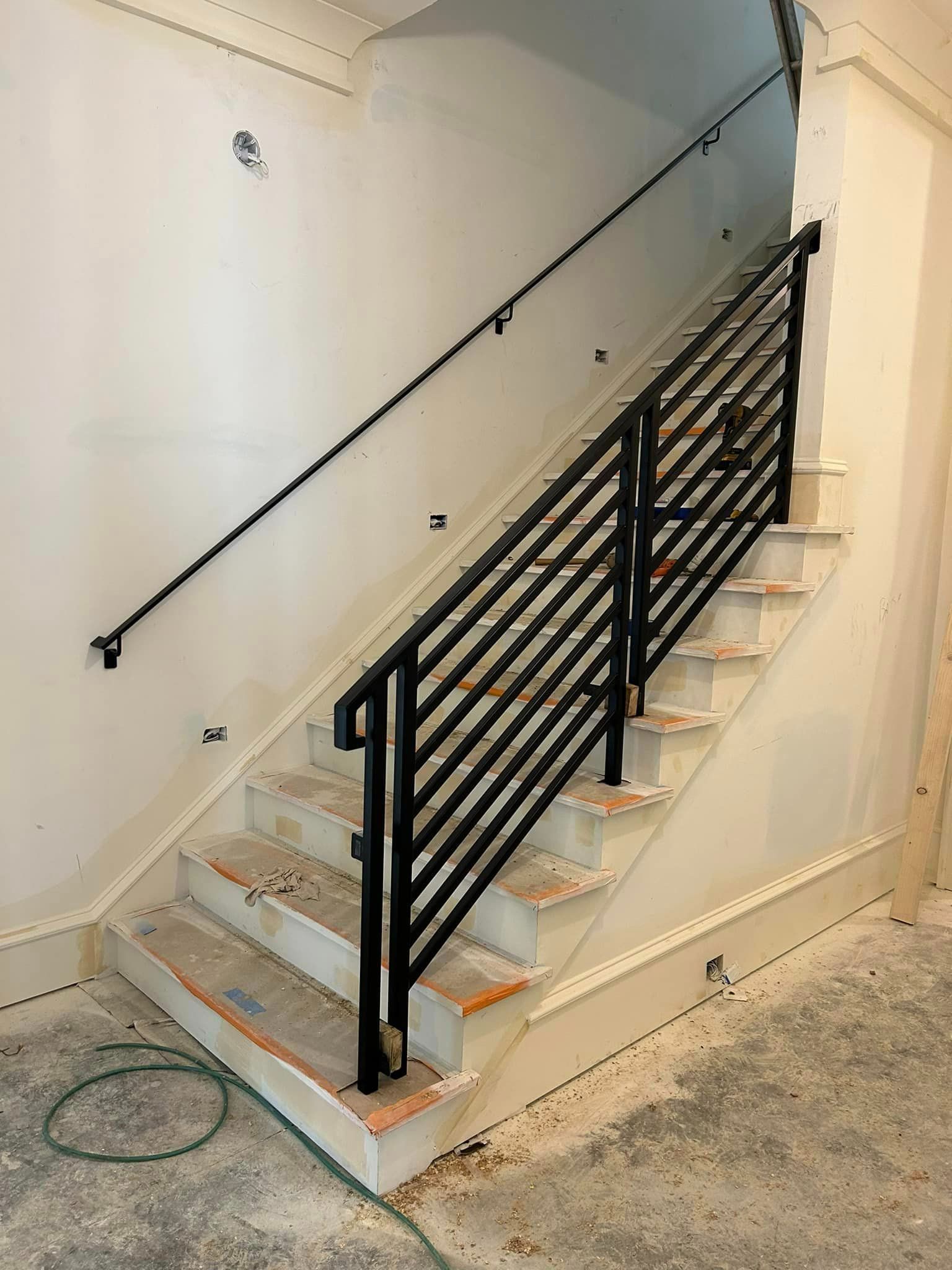 A staircase with a black railing is being built in a building.