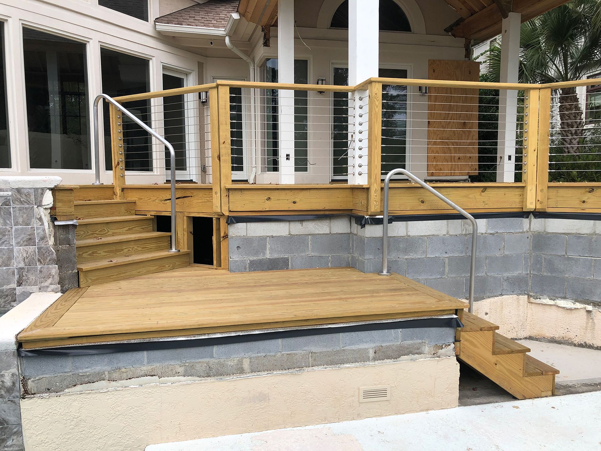 A wooden deck with stairs and a stainless steel railing