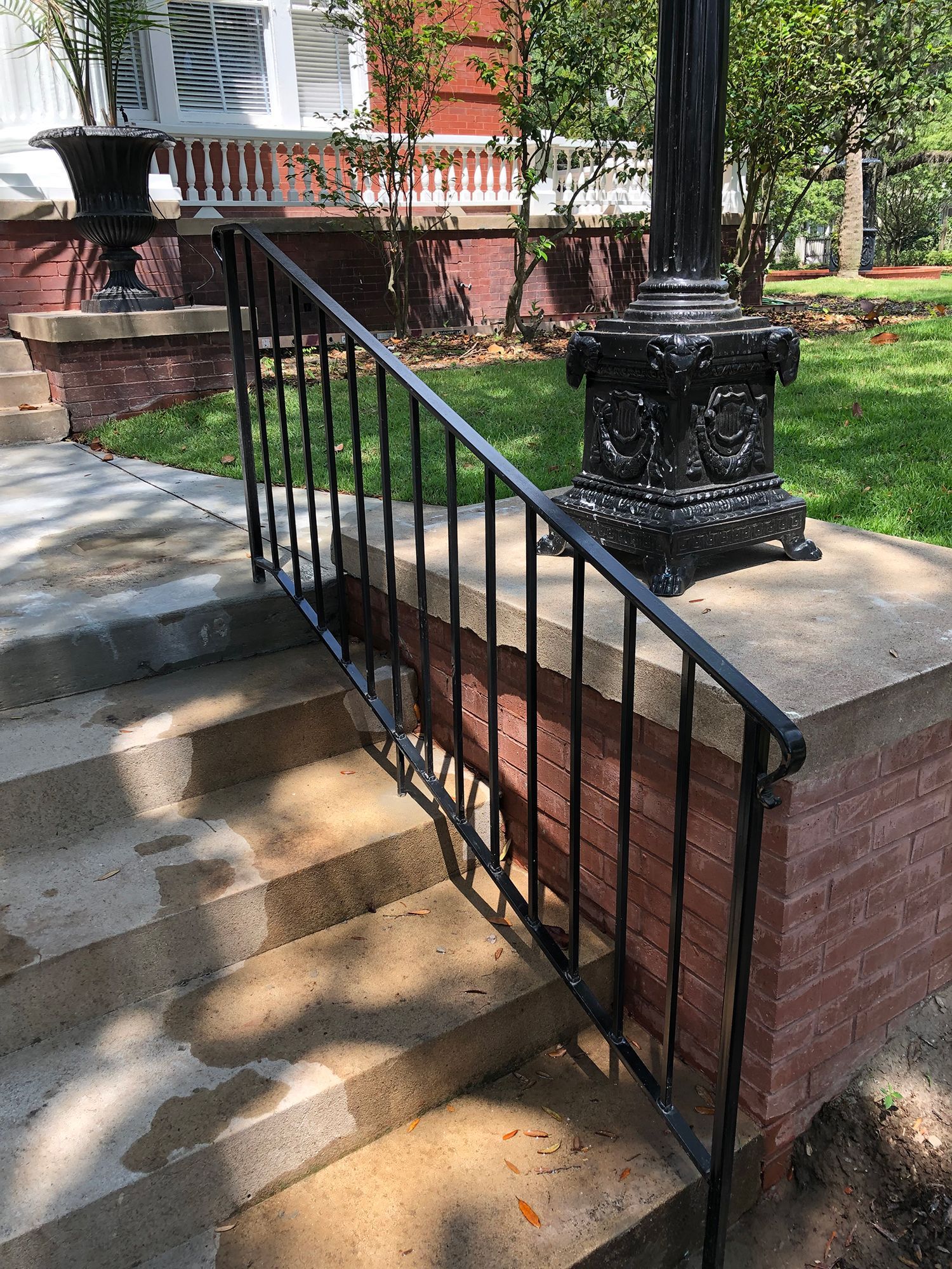 A black railing on a set of stairs next to a brick wall.
