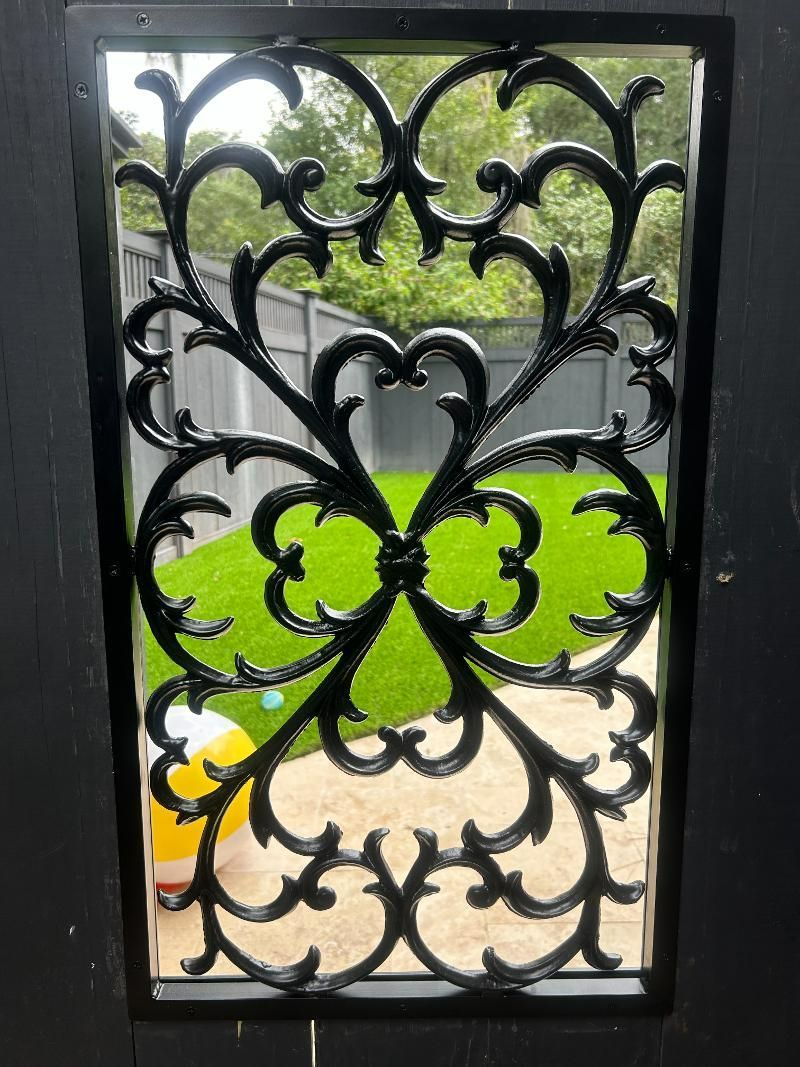 A black door with a wrought iron design on it.