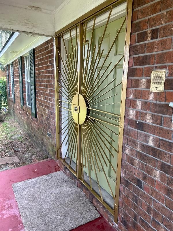 The front door of a brick house with a sunburst design on it.