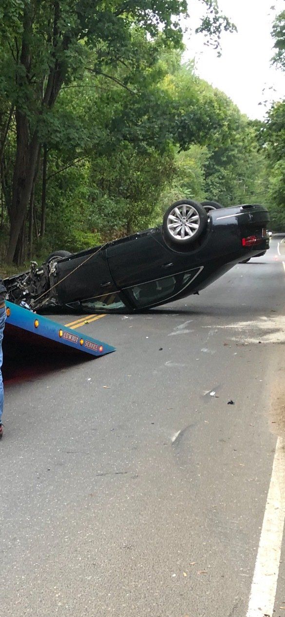 A car is on its side on the side of the road.