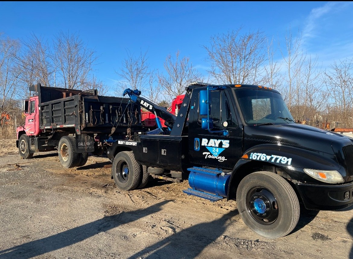 Two tow trucks are parked next to each other in a dirt lot.