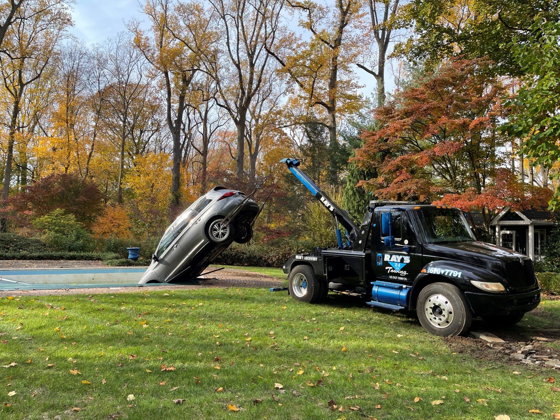 A tow truck is towing a car that has fallen into a pool.