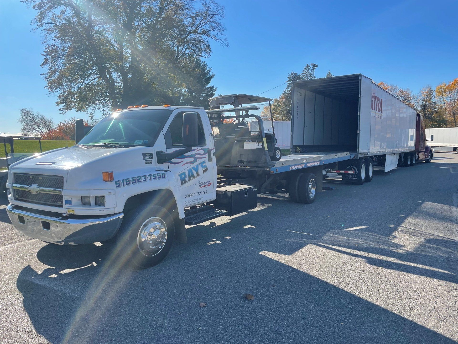 A tow truck with a trailer attached to it is parked on the side of the road.