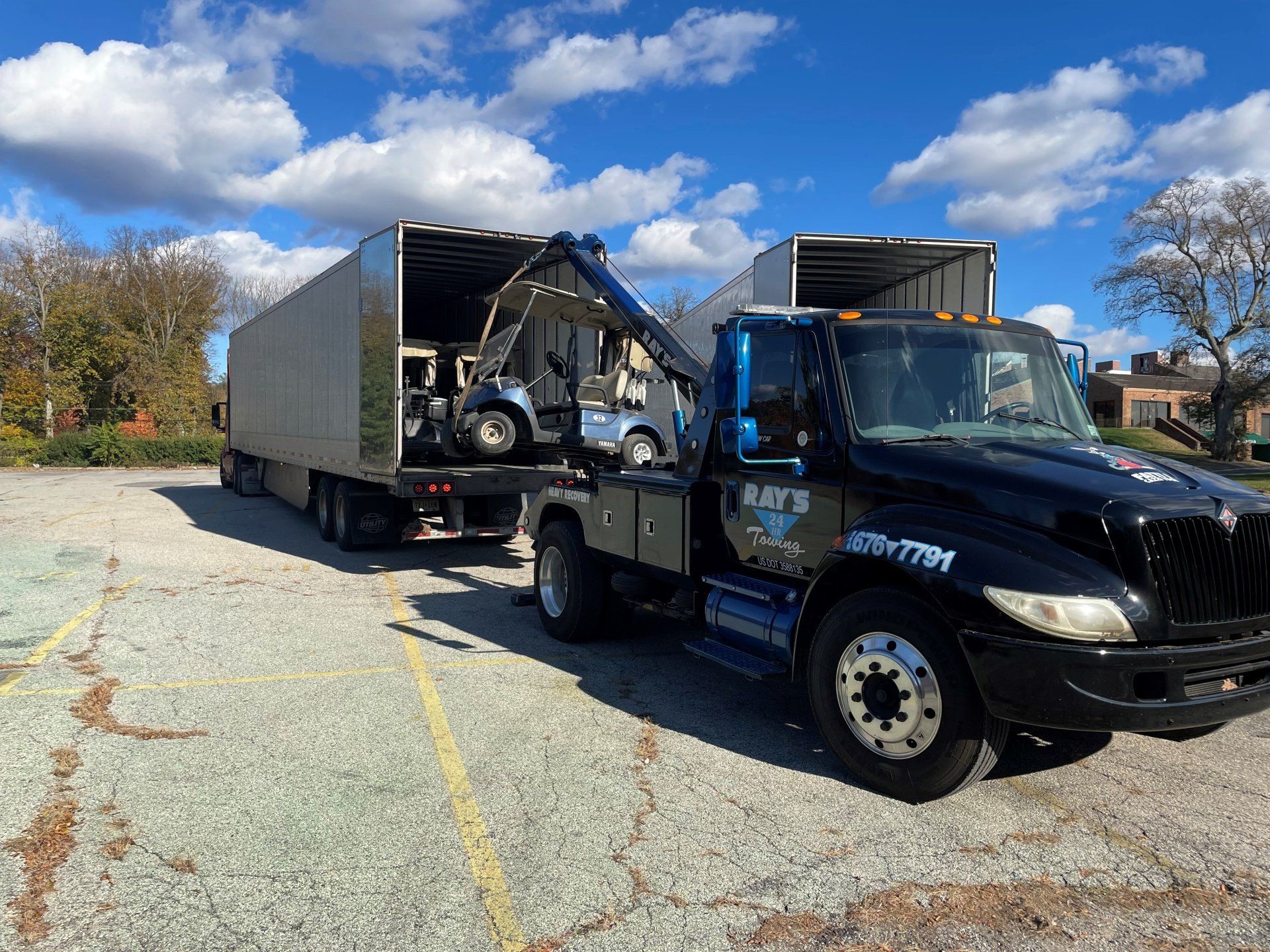 A tow truck is pulling a trailer with a golf cart in it.