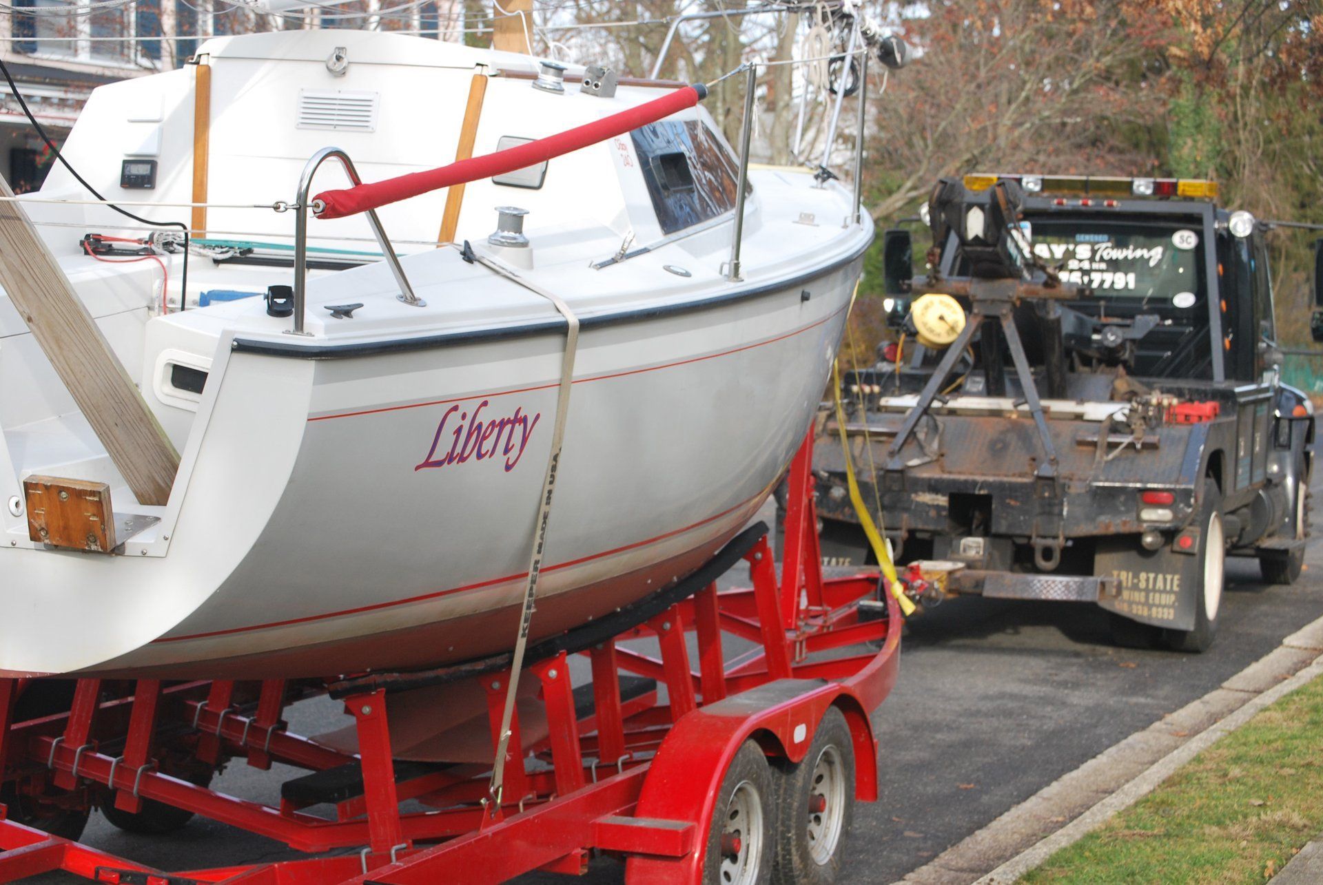 A boat named liberty is being towed by a tow truck
