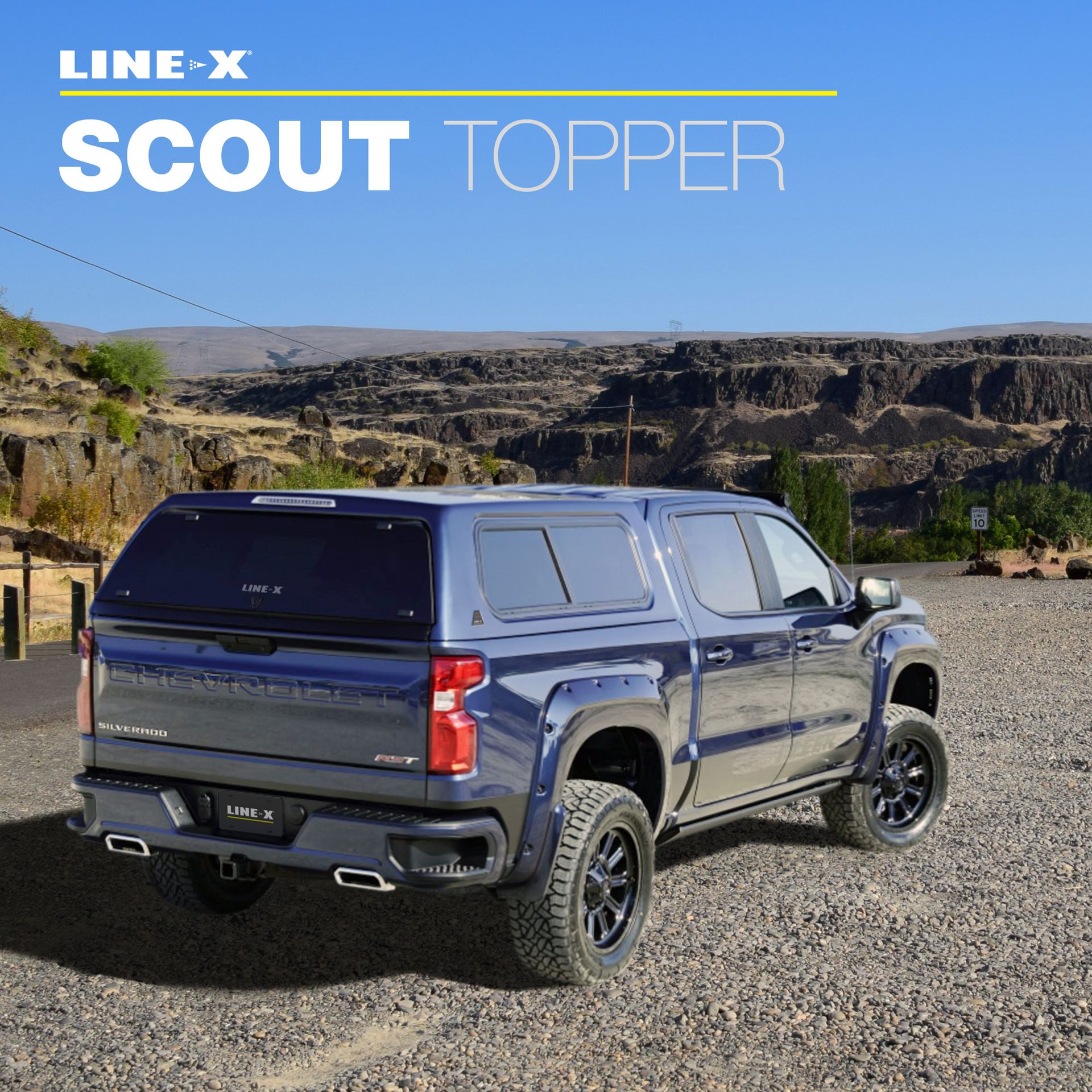 Blue pickup truck with Line-X Scout topper on gravel road, overlooking canyon landscape.