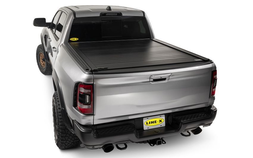 The back of a silver truck with a black tonneau cover.