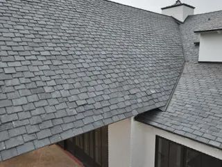 Gray shingled roof sections meeting at a dormer on a house exterior