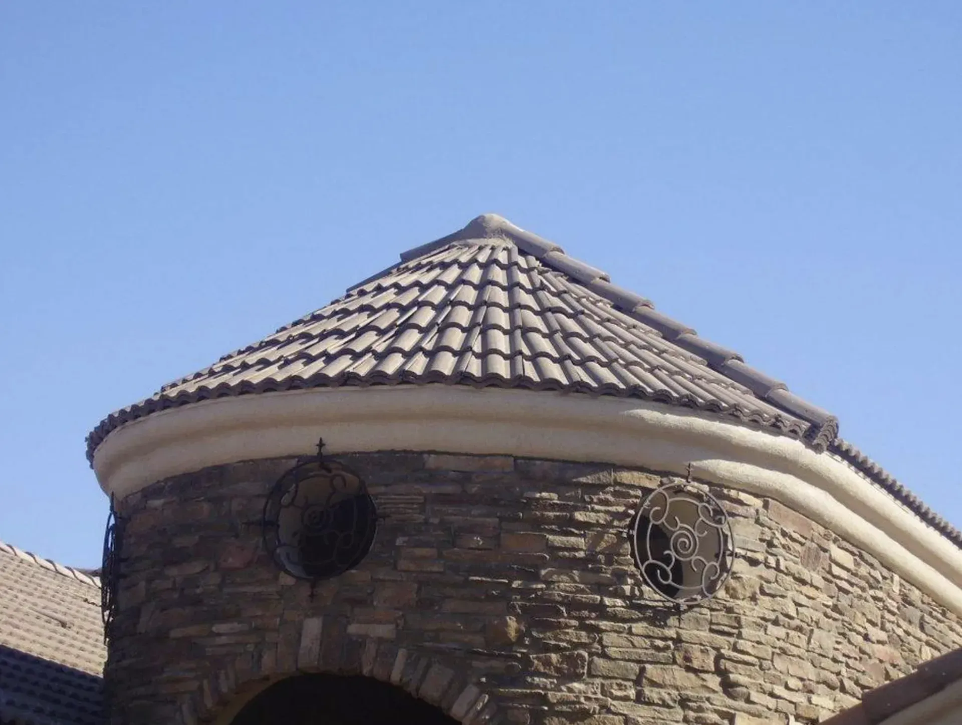 Stone tower with a tiled conical roof against a blue sky
