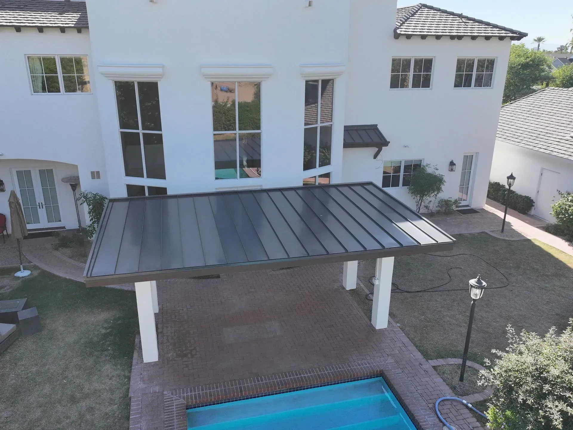 Modern white house with covered patio, backyard grass, and a blue swimming pool