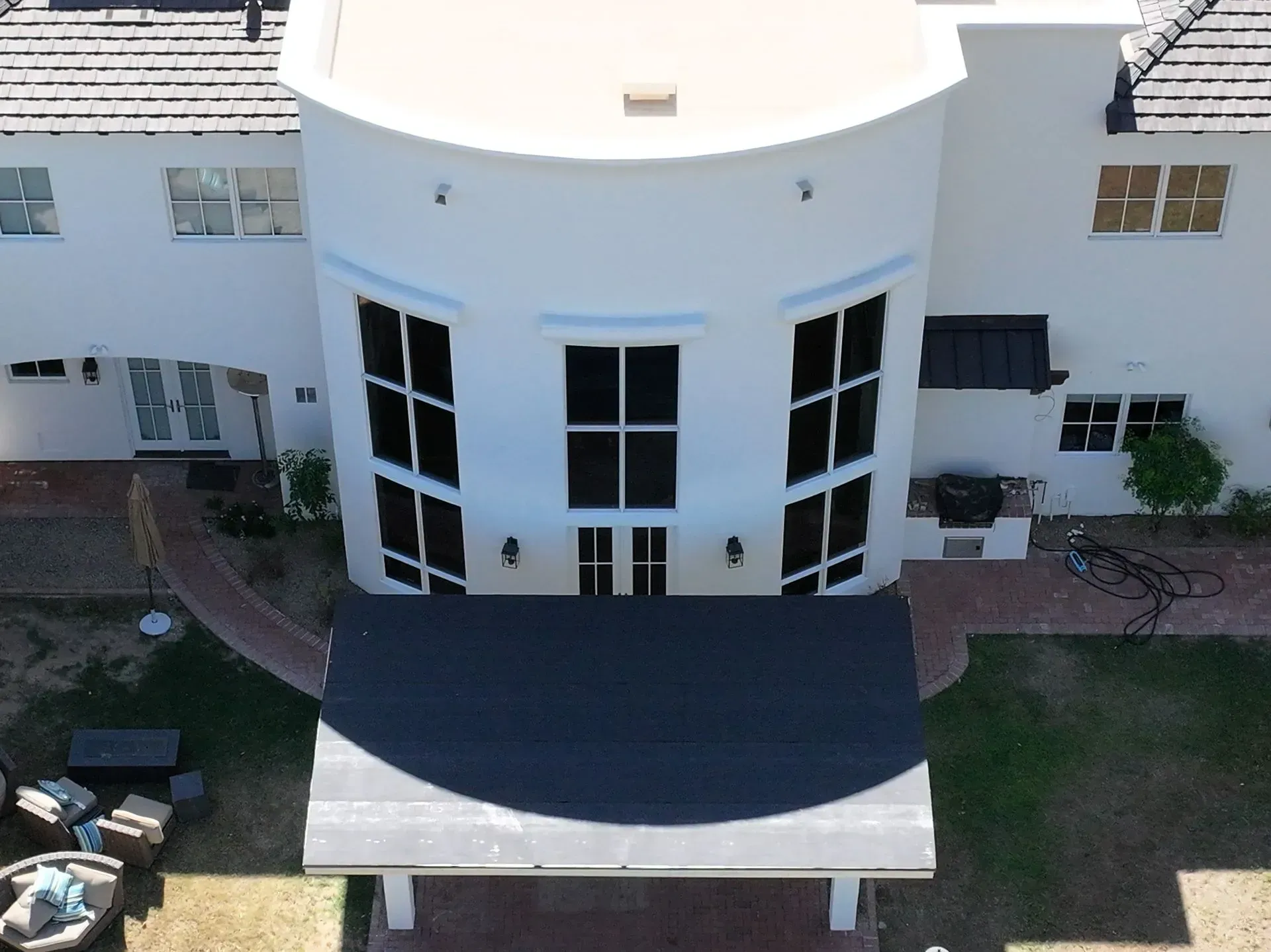 Aerial view of a white building with curved facade, dark awning, and brick walkways around it.