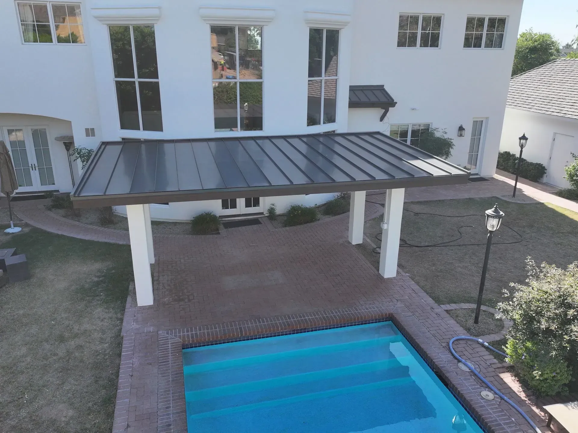 Backyard with a swimming pool and a covered patio beside a white house