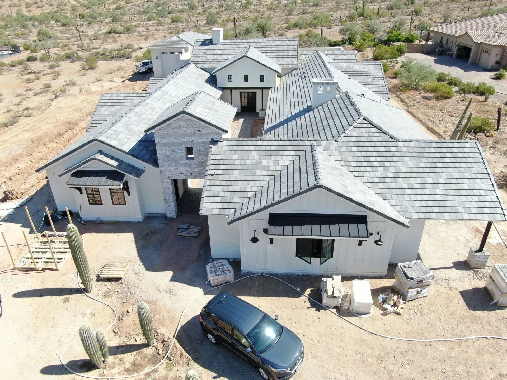 Aerial view of a modern gray house in a desert landscape with a car parked out front